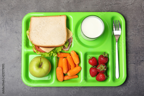 Serving tray with healthy food on gray background, top view. School lunch