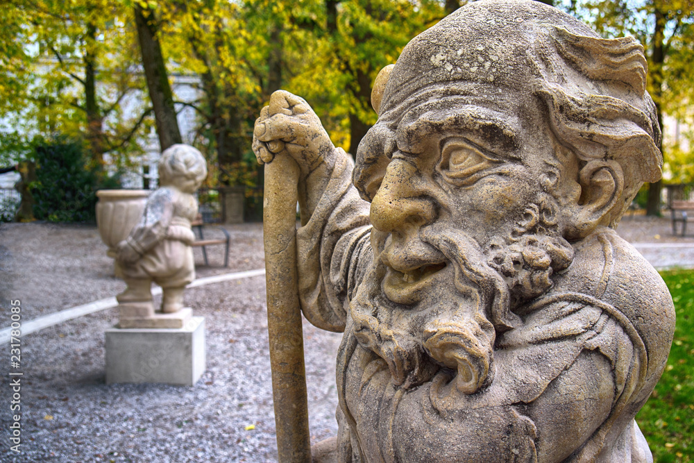 Stone statue of a dwarf. Marble sculpture of fairy gnome in Salzburg Mirabellgarten park, Salzburg, Austria