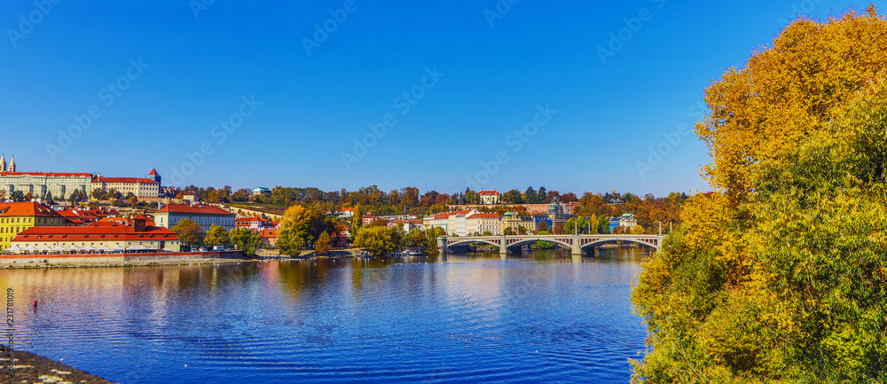 City view from bridge and traditional Czech architecture of antique Prague buildings at autumn evening.