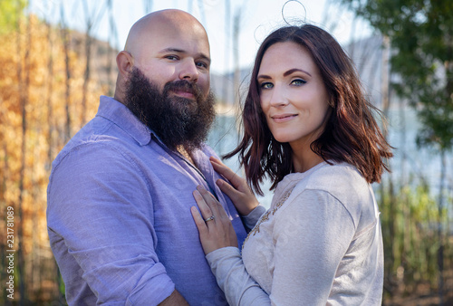 Couple in love by the lake looking into camera
