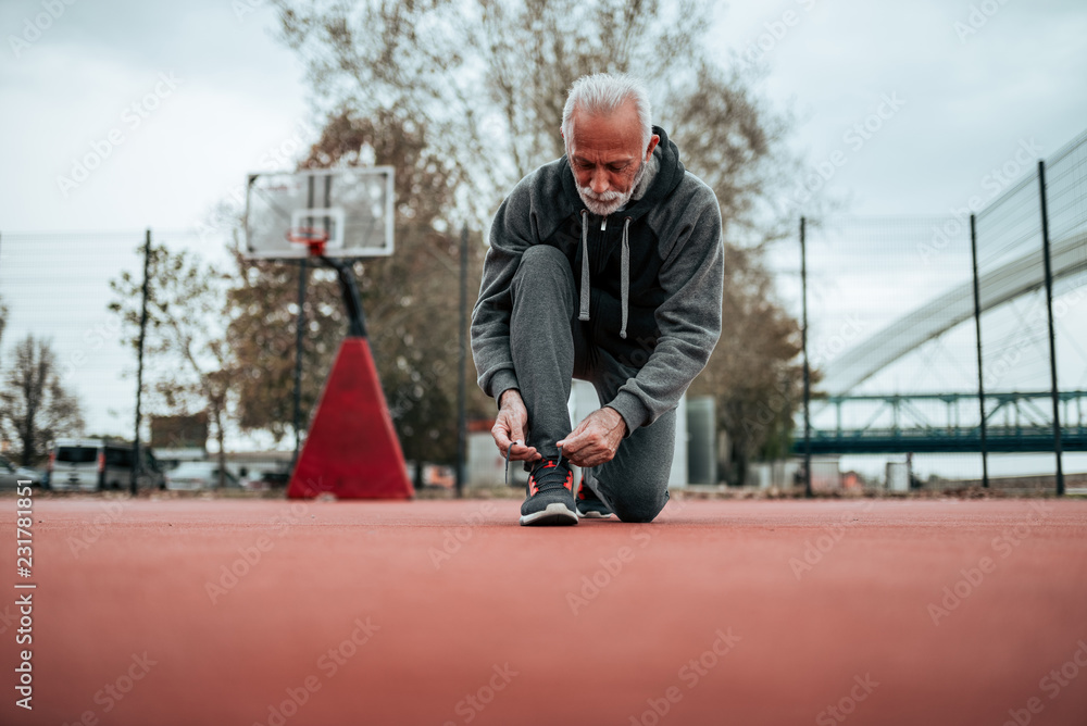 Active senior man in sportswear tying shoelaces before run outdoors. Active senior man in sportswear tying shoelaces before run outdoors.