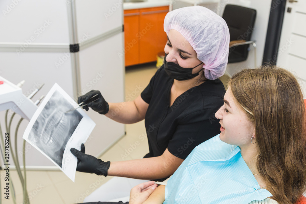 Dental clinic. Reception, examination of the patient. Teeth care. Female dentist in dental office talking with girl patient. Dental clinic. Reception, examination of the patient. Teeth care. Female dentist in dental office talking with girl patient.