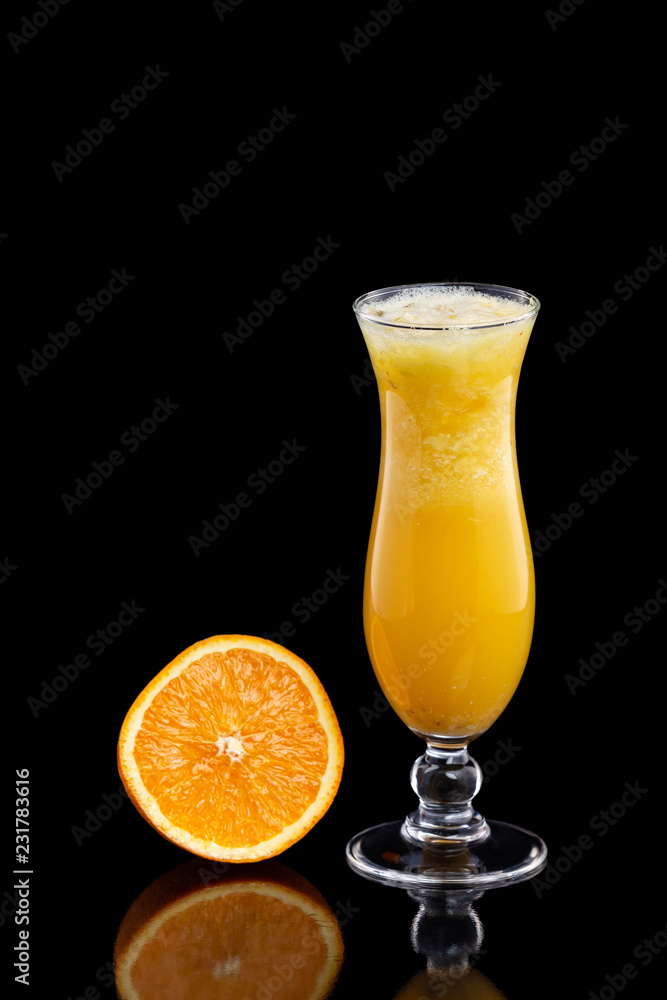 Closeup glass of fresh orange juice with ice isolated at black background.