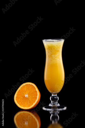 Closeup glass of fresh orange juice with ice isolated at black background.