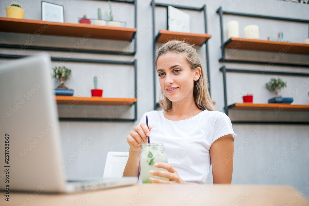 Student girl drinking lemonade and looking at laptop. Student girl drinking lemonade and looking at laptop.