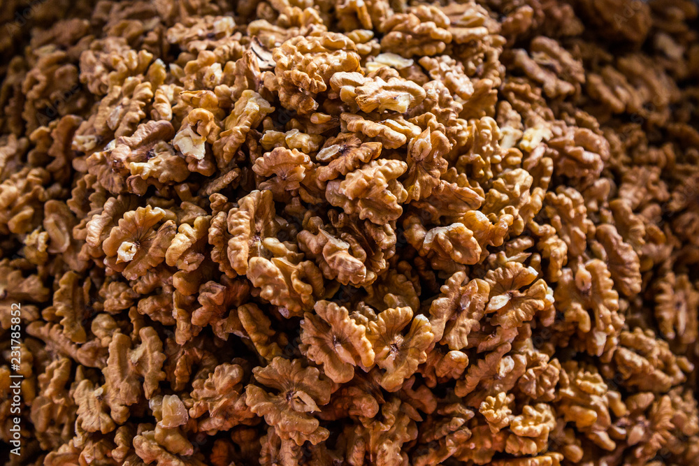 Obraz premium Many walnuts lie on the market and in the store. Open and peeled nuts are full of vitamins, a fresh and healthy snack for vegetarians. Shelled nuts in curved forms. Big plates on the market.