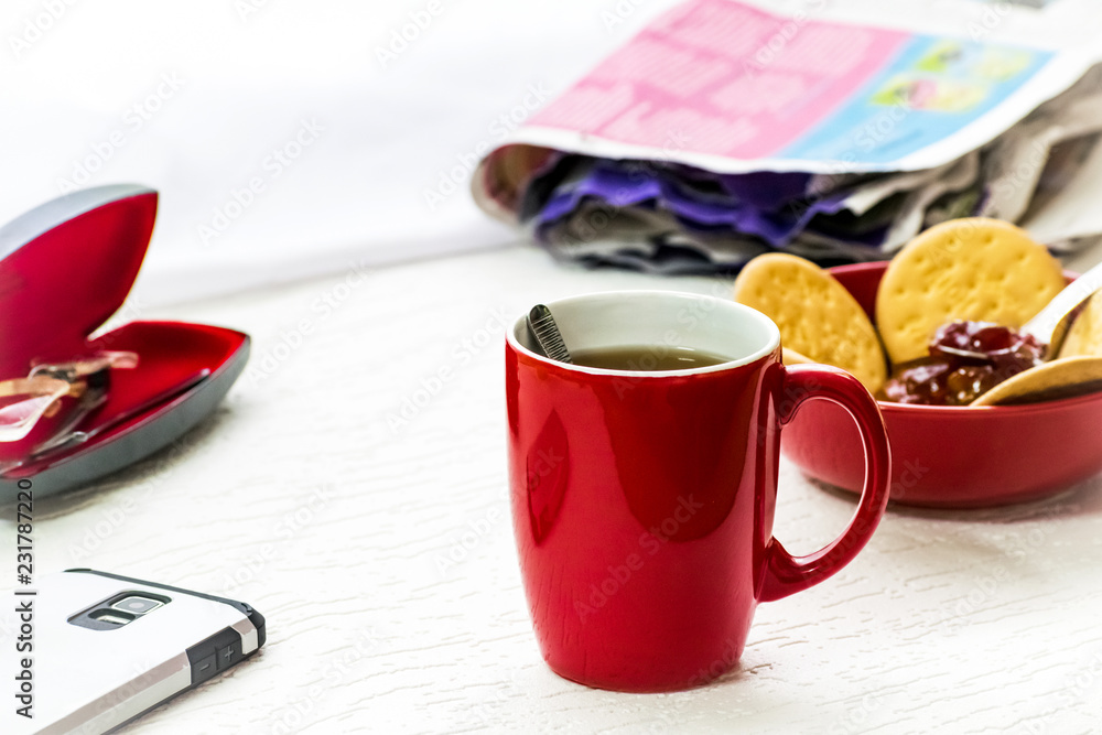 Side View Closeup of Fresh breakfast table in the morning with tea , biscuits , newspaper and mobile on a white background Side View Closeup of Fresh breakfast table in the morning with tea , biscuits , newspaper and mobile on a white background