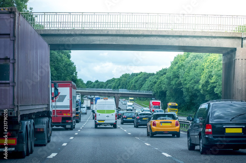 Closeup of two vans driving on left and right on a Busy motorway full of cars in the evening with dark cloudy blue sky