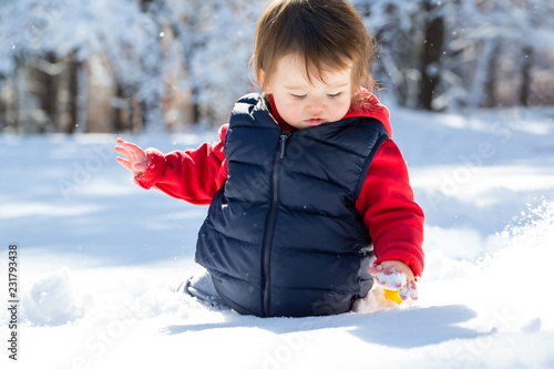 Toddler boy playing in the snow on a winter day