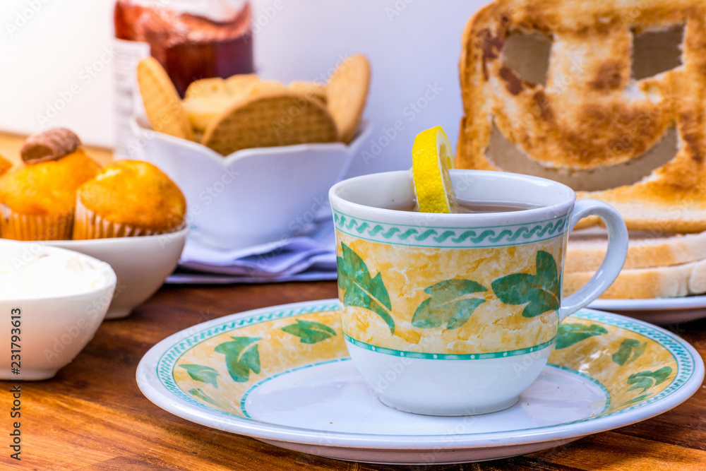 Fototapeta premium Closeup of Fresh morning breakfast with hot tea and lemon, funny face toast, cake, yogurt on a brown wooden table , dairy products.