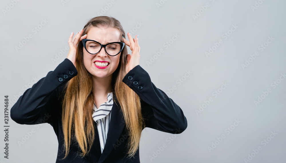Young woman suffering from headache on a gray background Young woman suffering from headache on a gray background
