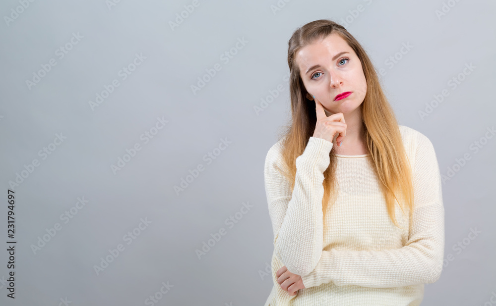 Young woman in a thoughtful pose on a gray background Young woman in a thoughtful pose on a gray background