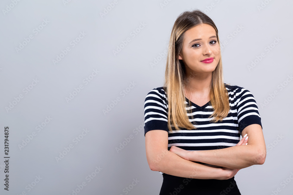Young woman with crossed arms on a gray background Young woman with crossed arms on a gray background