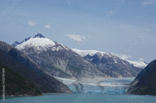Endicott Arm, Alaska, USA: The Dawes Glacier flows down from snow-capped mountains through a valley at the end of a fjord in the Pacific Northwest.