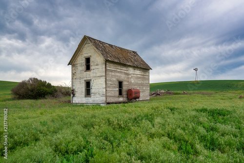abandoned house in field with windmill