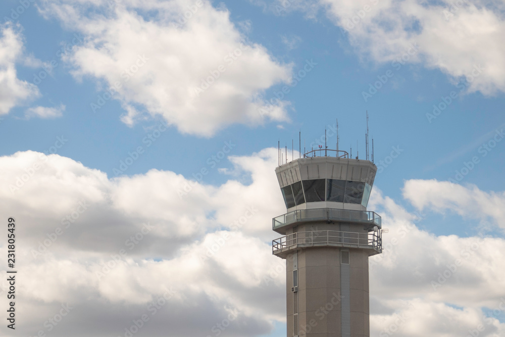 Airport control tower on a sunny day against blue sky with fluffy white clouds Airport control tower on a sunny day against blue sky with fluffy white clouds