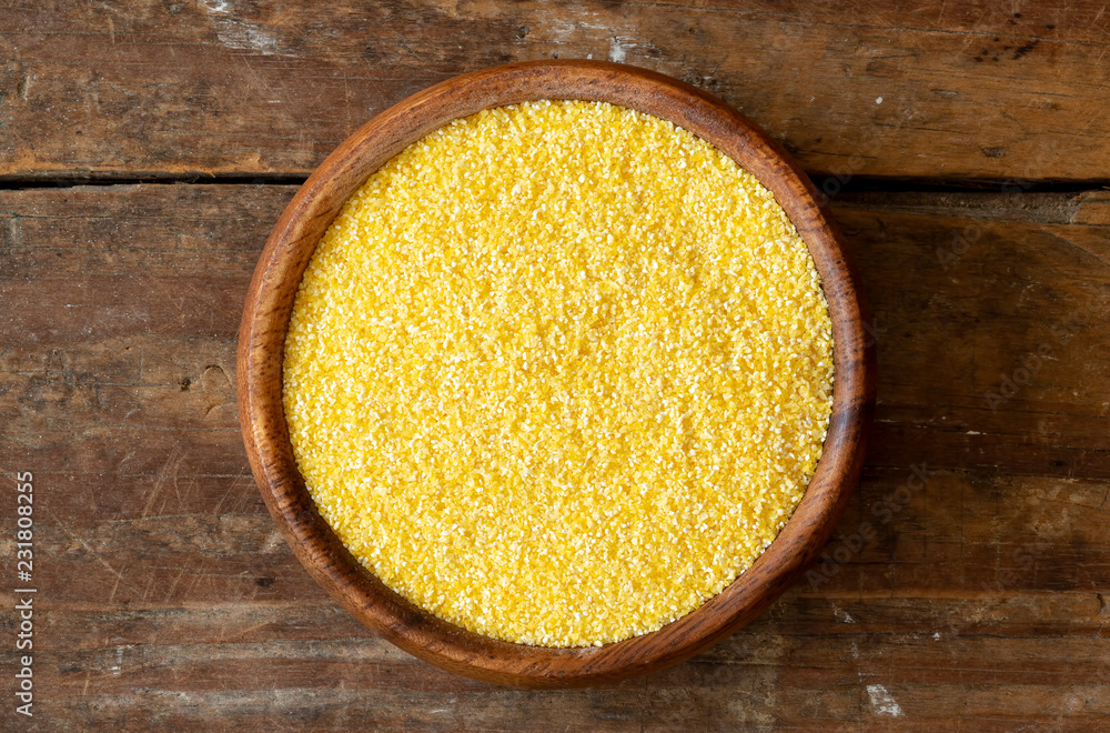 Fine ground yellow corn meal in wood bowl. Fine ground yellow corn meal in wood bowl.