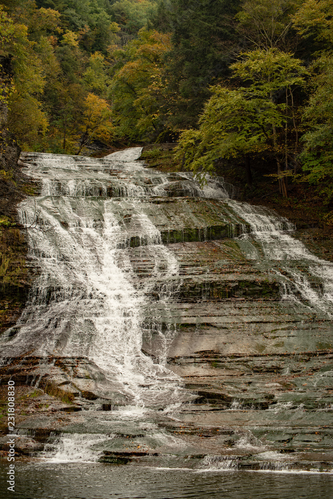 Obraz premium Waterfall cascading over the rocks in Buttermilk falls state park, New York