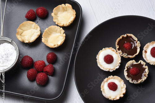 Murais de parede Flat lay of chocolate and vanilla custard fillo shells topped with raspberries