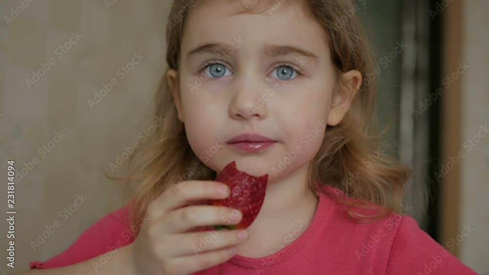 Happy child little girl drinks eats strawberries in the summer home kitchen. Happy child little girl drinks eats strawberries in the summer home kitchen.