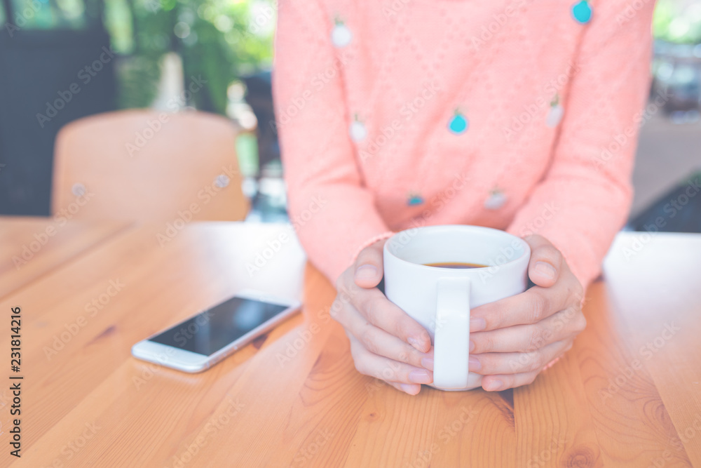 Woman hand in warm sweater holding a cup of coffee. Woman hand in warm sweater holding a cup of coffee.