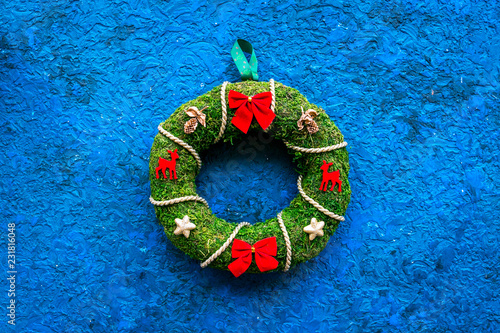 Christmas wreath traditional, classic type. Wreath made of spruce branches and red ribbons on blue background top view space for text