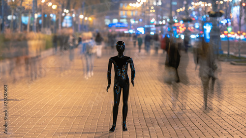 The mannequin stands on the street among the stream of people