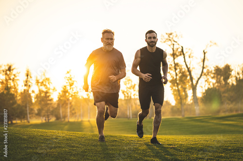 The two men running on the grass against the sunny background