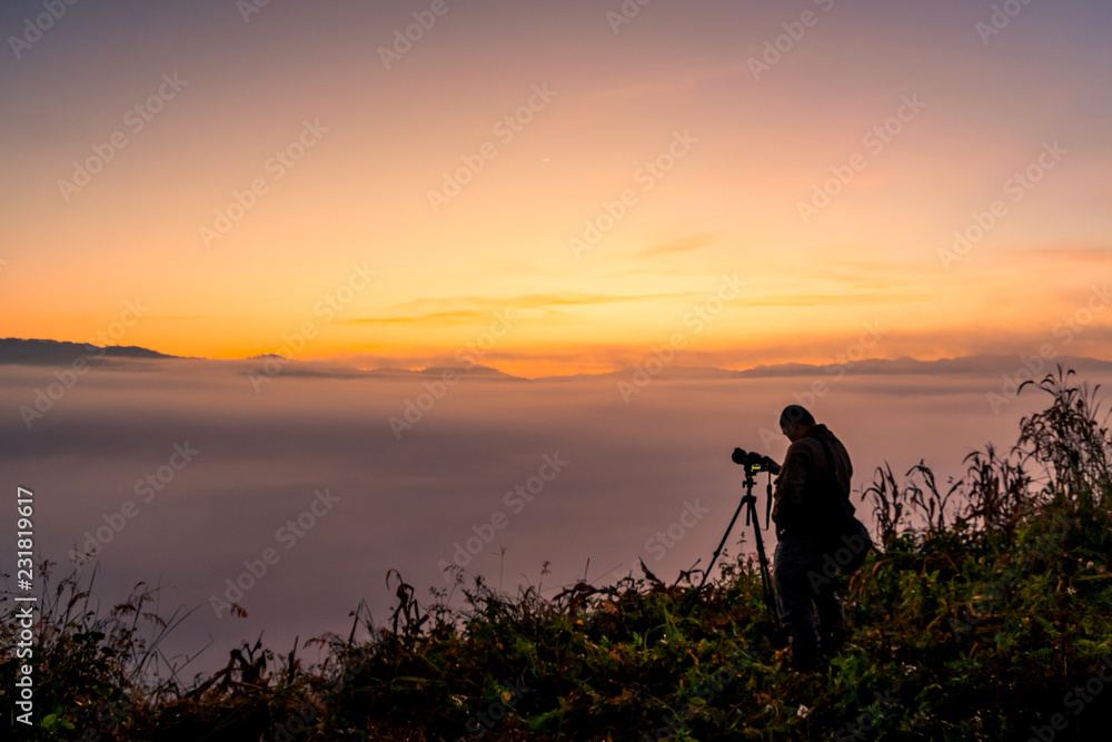 Photographer take photos with mirror camera on peak of mountain. misty landscape, spring orange pink misty sunrise in beautiful valley below. Photographer take photos with mirror camera on peak of mountain. misty landscape, spring orange pink misty sunrise in beautiful valley below.