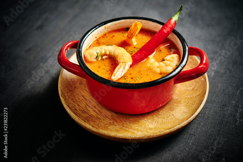 traditional Thai soup with shrimp and coconut milk in a red pot with chilli pepper
