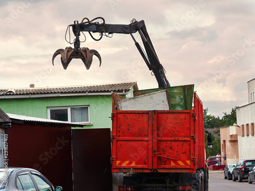 Magnet grapple picking up iron and steel metal garbage for transferring and recycling. Truck with metal grab is loading industrial and household waste on scrap yard. Demolition and sorting concept
