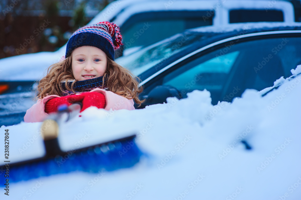 kid girl helping to clean car from snow on winter backyard or parking. Car covered with snow after blizzard kid girl helping to clean car from snow on winter backyard or parking. Car covered with snow after blizzard