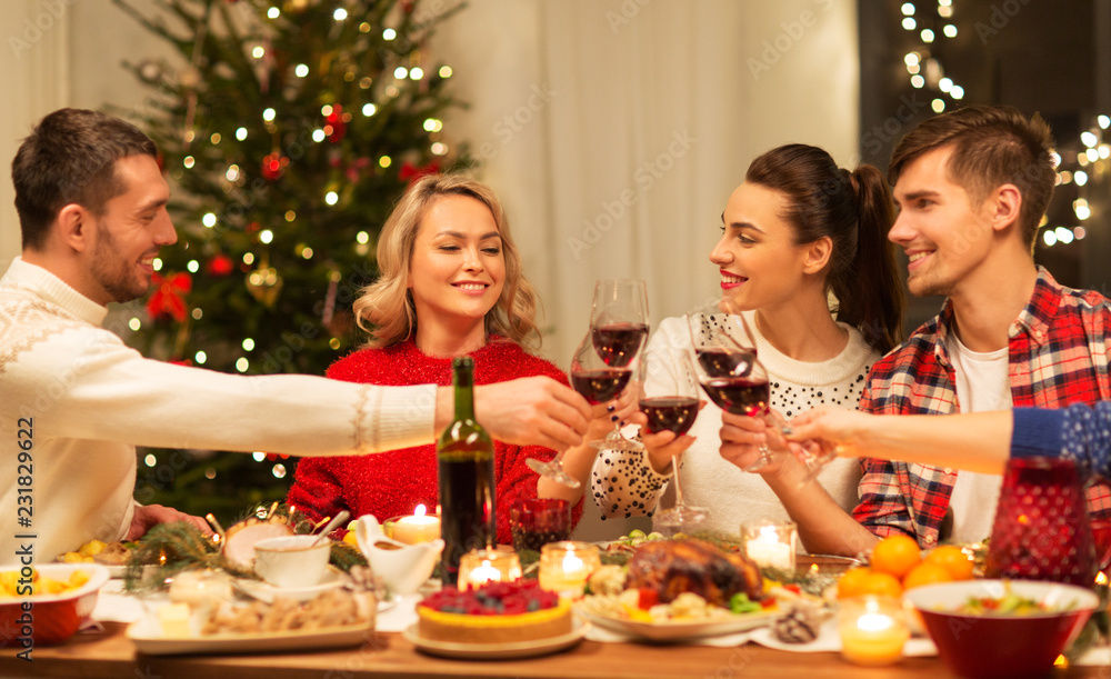 holidays and celebration concept - happy friends having christmas dinner at home, drinking red wine and clinking glasses holidays and celebration concept - happy friends having christmas dinner at home, drinking red wine and clinking glasses