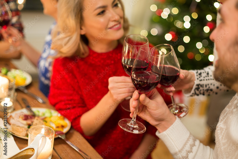 holidays and celebration concept - close up of happy friends having christmas dinner at home, drinking red wine and clinking glasses holidays and celebration concept - close up of happy friends having christmas dinner at home, drinking red wine and clinking glasses