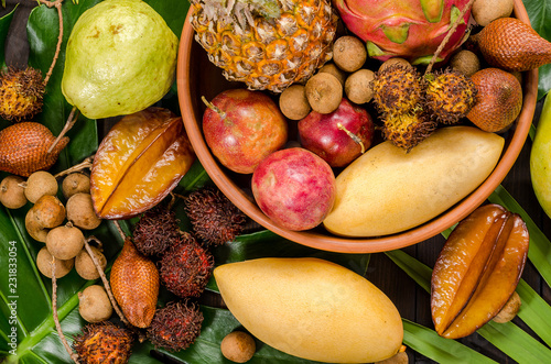 Assorted Thai tropical fruits on a dark wooden rustic background. photo