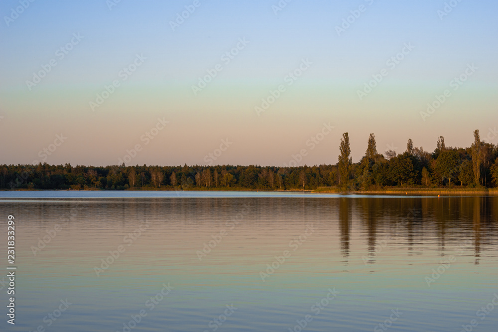 Blue lake with cloudy sky, nature series, a lake landscape with reflection from some trees.