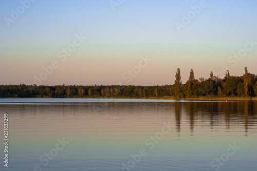 Blue lake with cloudy sky, nature series, a lake landscape with reflection from some trees.
