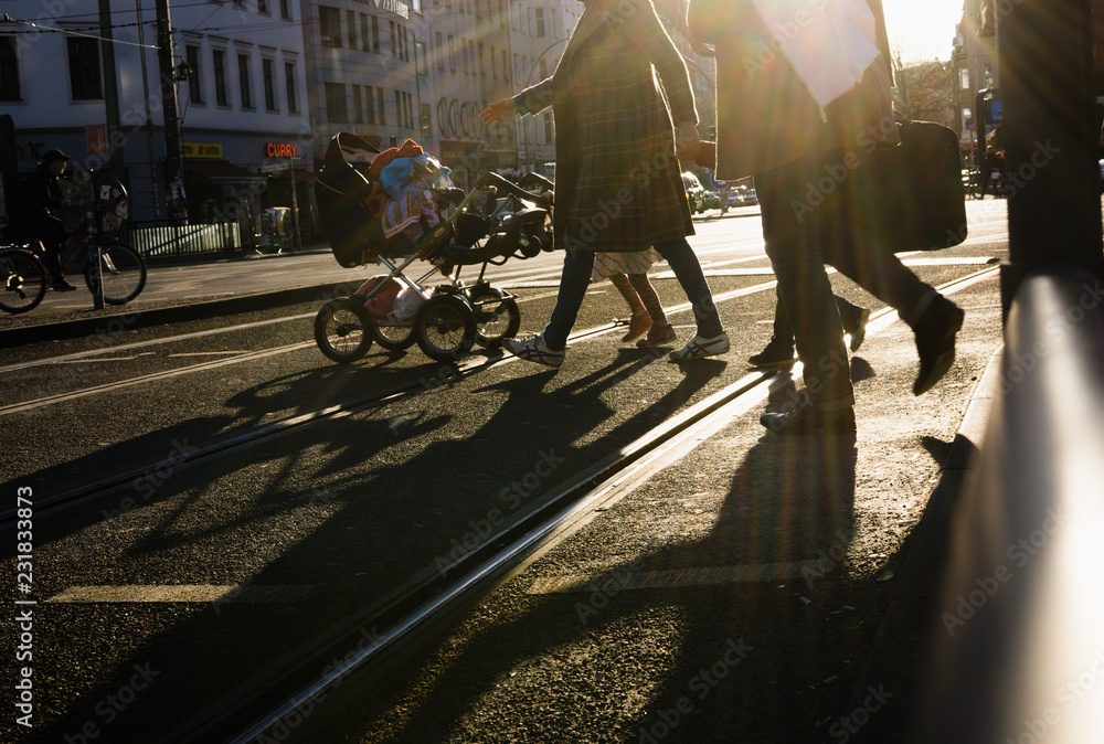 Anonymous people crossing street in sunset