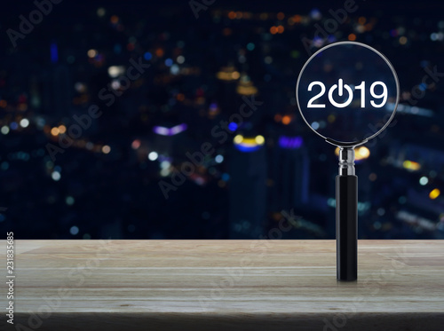 2019 start up flat icon with magnifying glass on wooden table over blur colorful night light city towerand skyscraper, Business happy new year 2019 concept photo