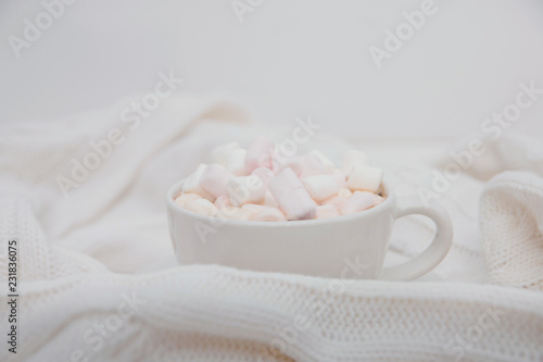 hot chocolate with marshmallows on a white knitted sweater. Copy space