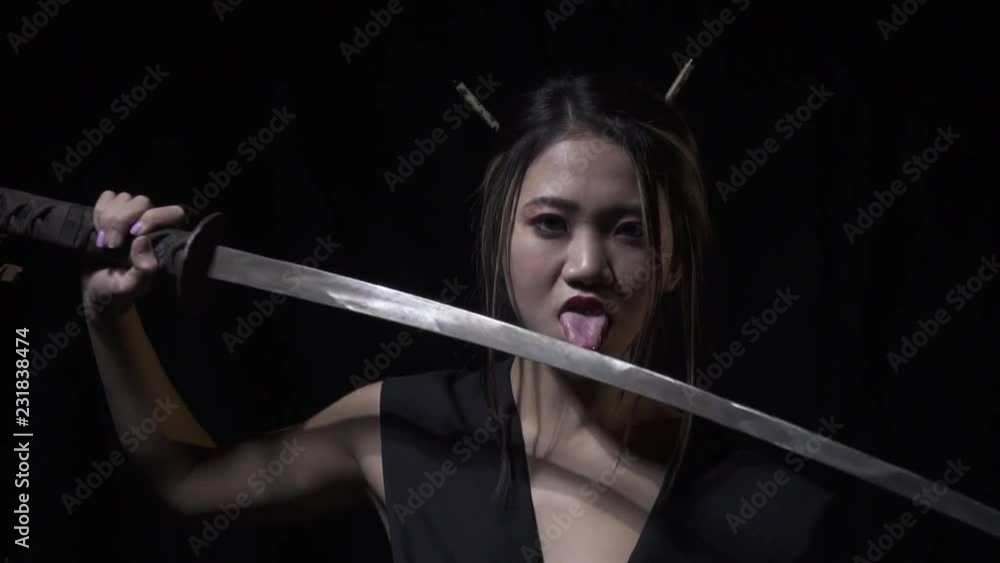Samurai woman licks katana while pulling it out, slow motion Samurai woman licks katana while pulling it out, slow motion