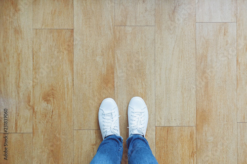 Selfie of feet in fashion sneakers on wooden floor background, top view with copy space photo