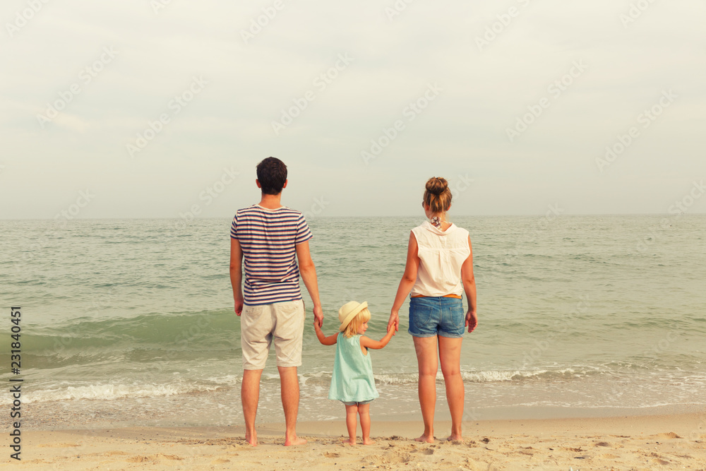 Happy family! Dad, mother and daughter are standing on the seashore. Back view.