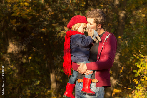 Dad is kissing the forehead of his tiny daughter in an autumn park at sunset. © AnastazjaSoroka