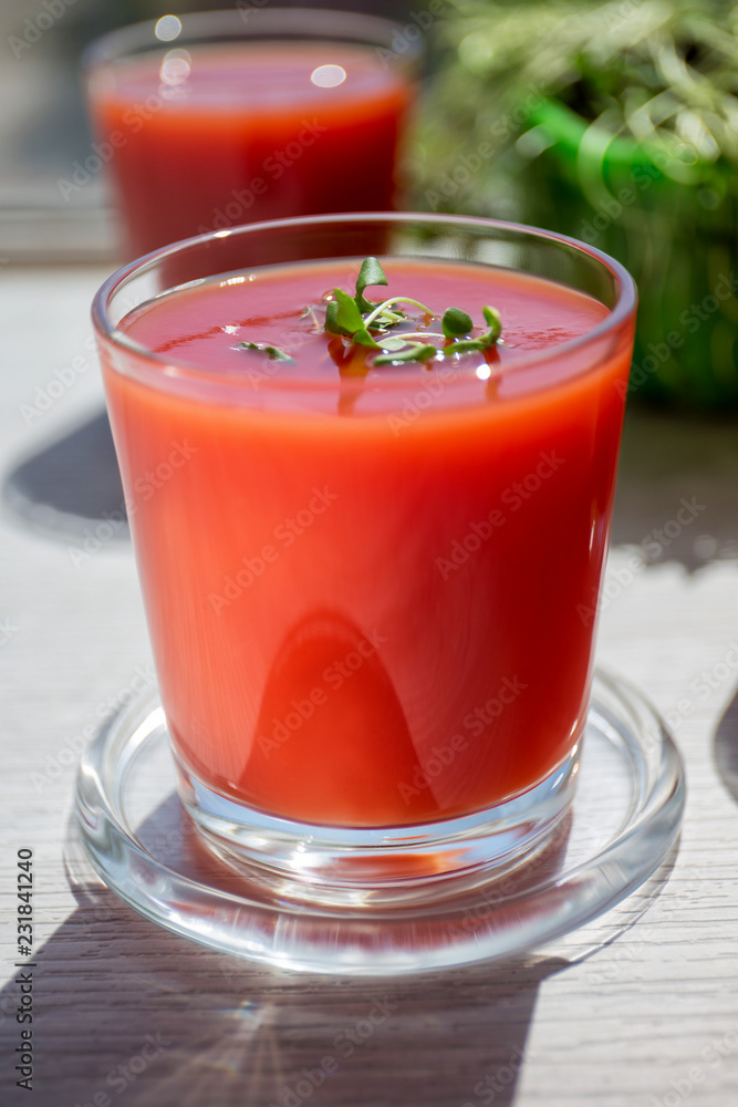 Red tomato juice in a glass, bright morning sun, healthy breakfast Red tomato juice in a glass, bright morning sun, healthy breakfast