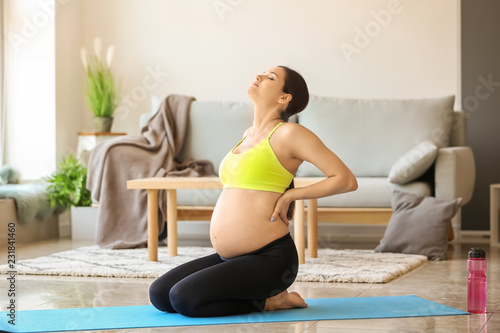 Young pregnant woman practicing yoga at home