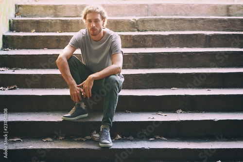 Lonely young man sitting on stairs outdoors © Pixel-Shot