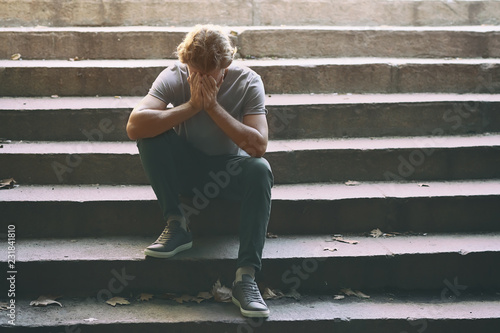 Stressed young man sitting on stairs outdoors photo