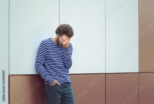 Stressed young man near wal...