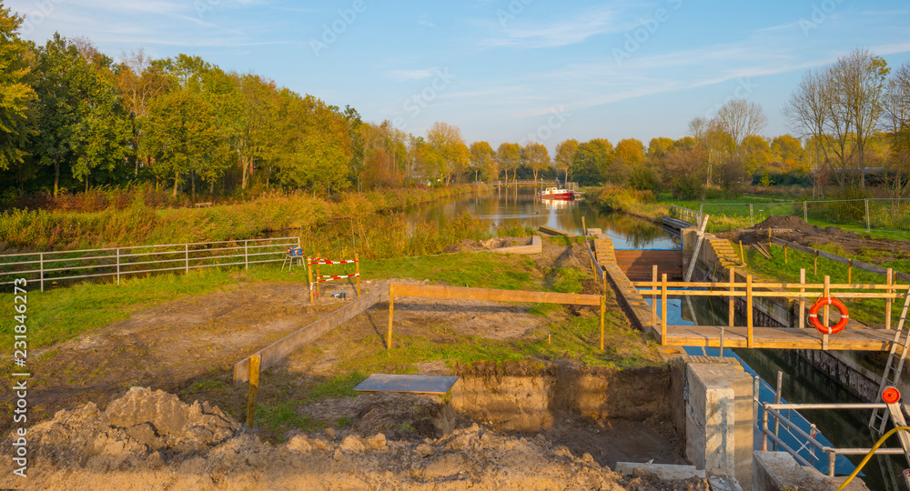 Construction of a sluice in a canal in a city in sunlight at fall Construction of a sluice in a canal in a city in sunlight at fall